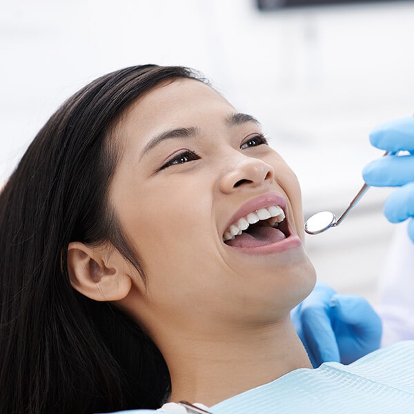 A woman at the dentist smiling as they are about to have her teeth cleaned