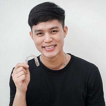 A teenage boy holding a set of invisalign® aligners